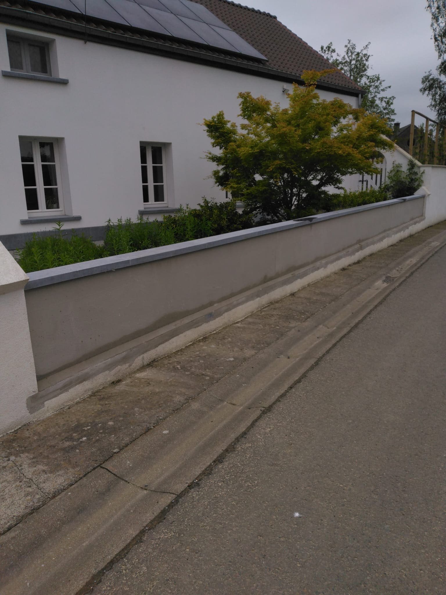 Mur de clôture enduit le long de la rue, chaperon compris
